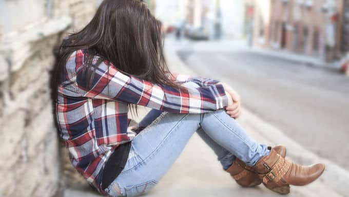 a woman sitting on the sidewalk