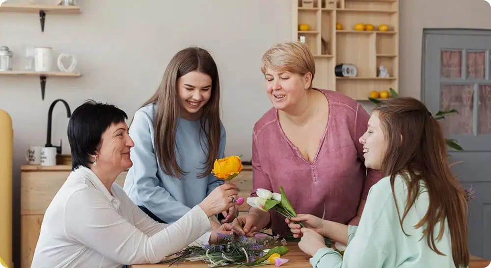 Women and girls exchanging flowers in a warm, supportive environment.
