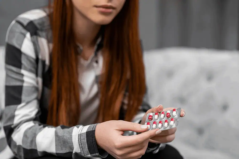 Woman holding a blister pack of birth control pills for women's health.