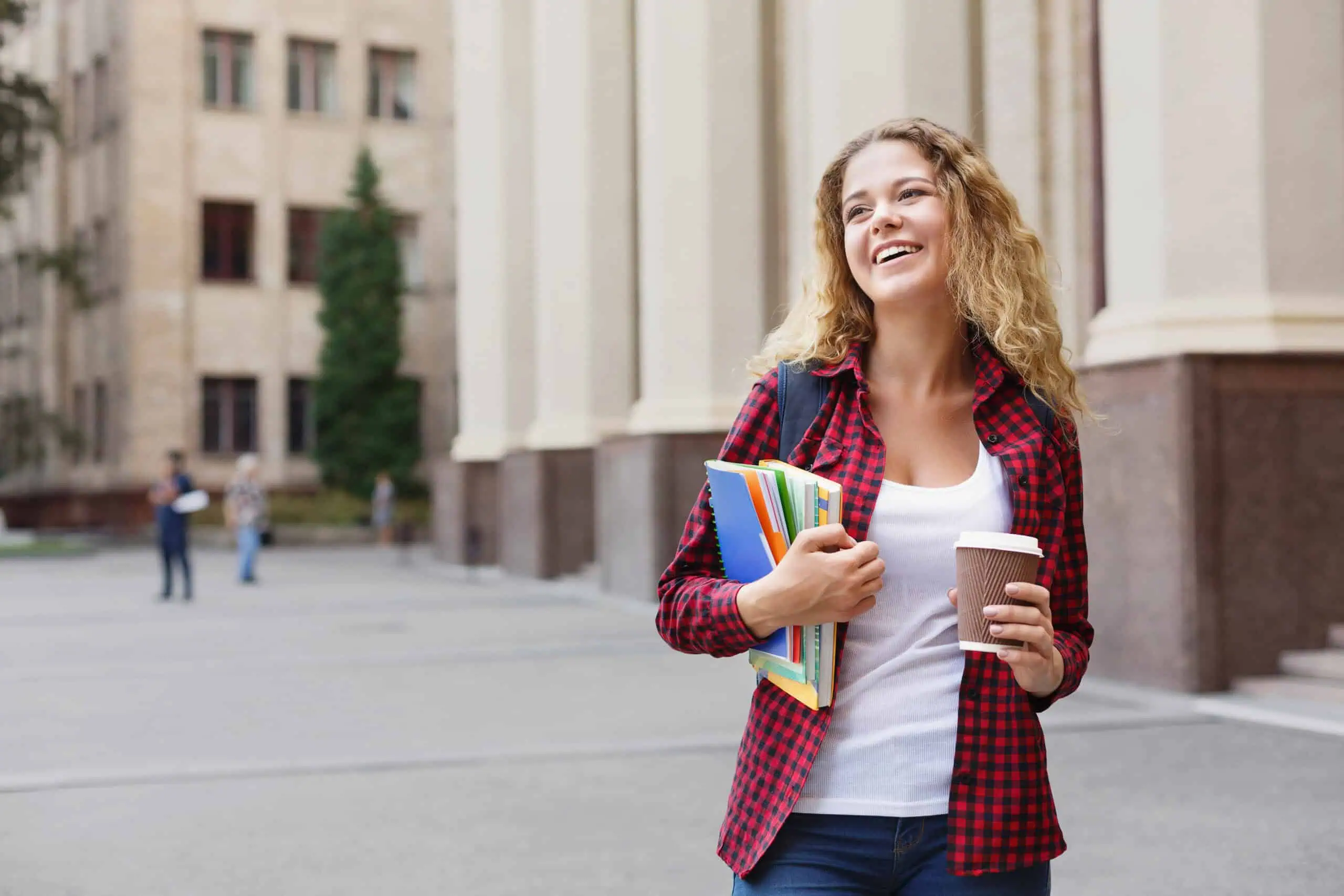 Smiling female college student holding notebooks near UC Riverside campus