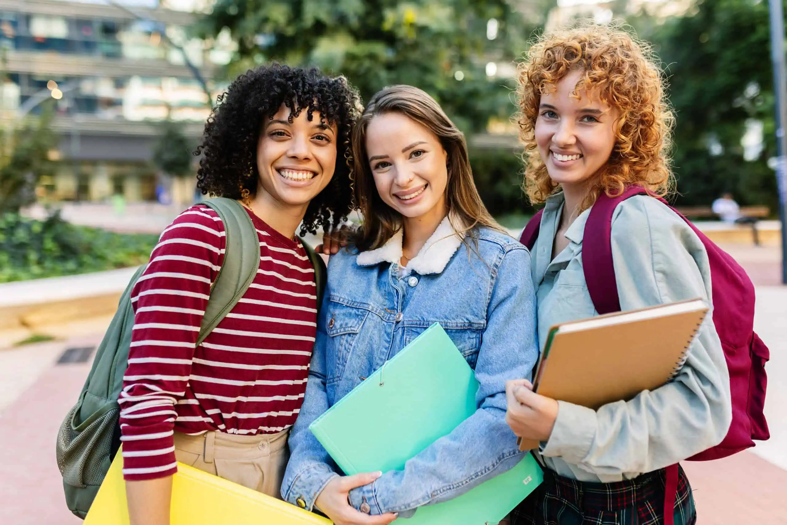 Three young women smiling together on the UC Riverside campus
