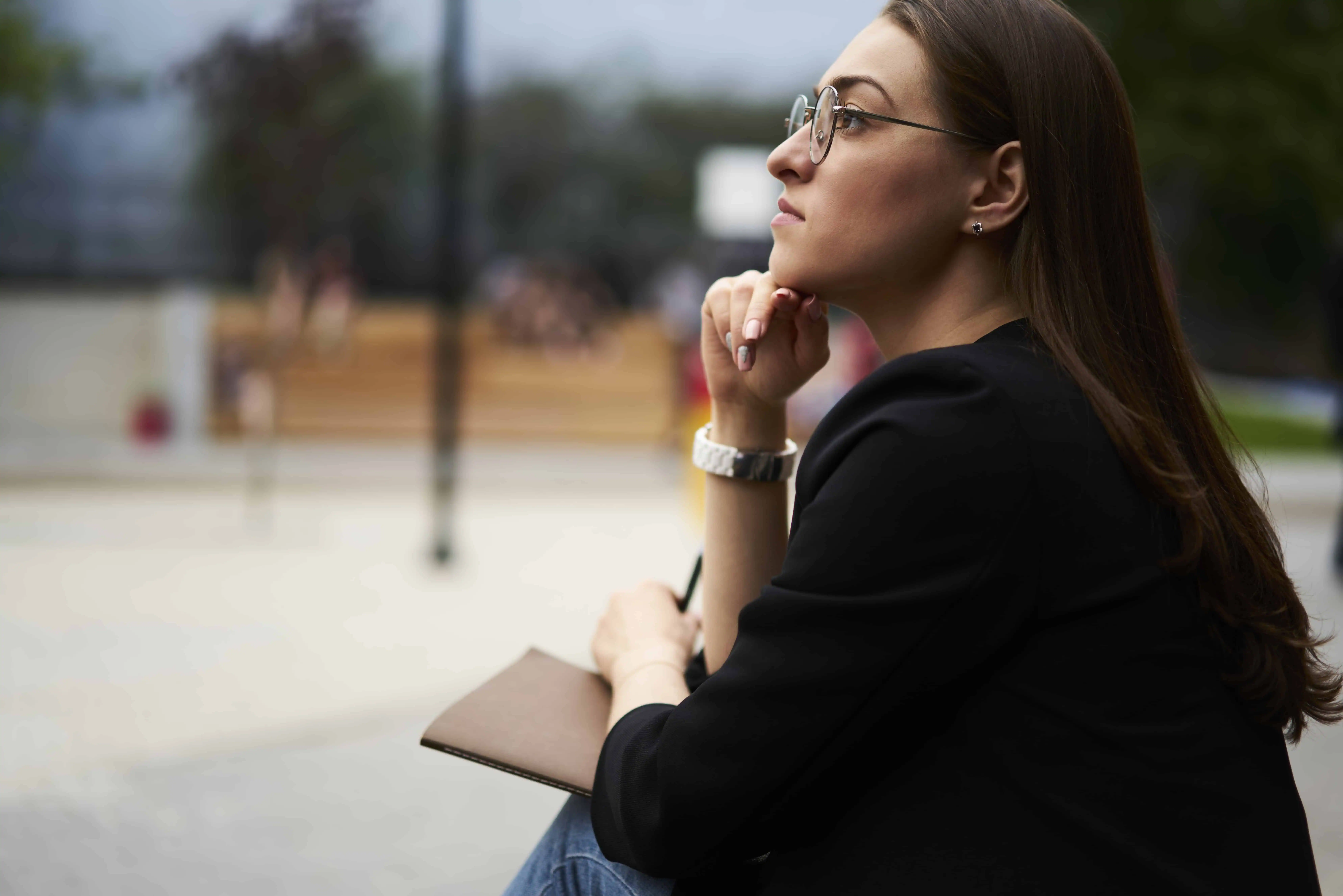Woman in black blazer thinking outdoors, representing women's health and wellness.