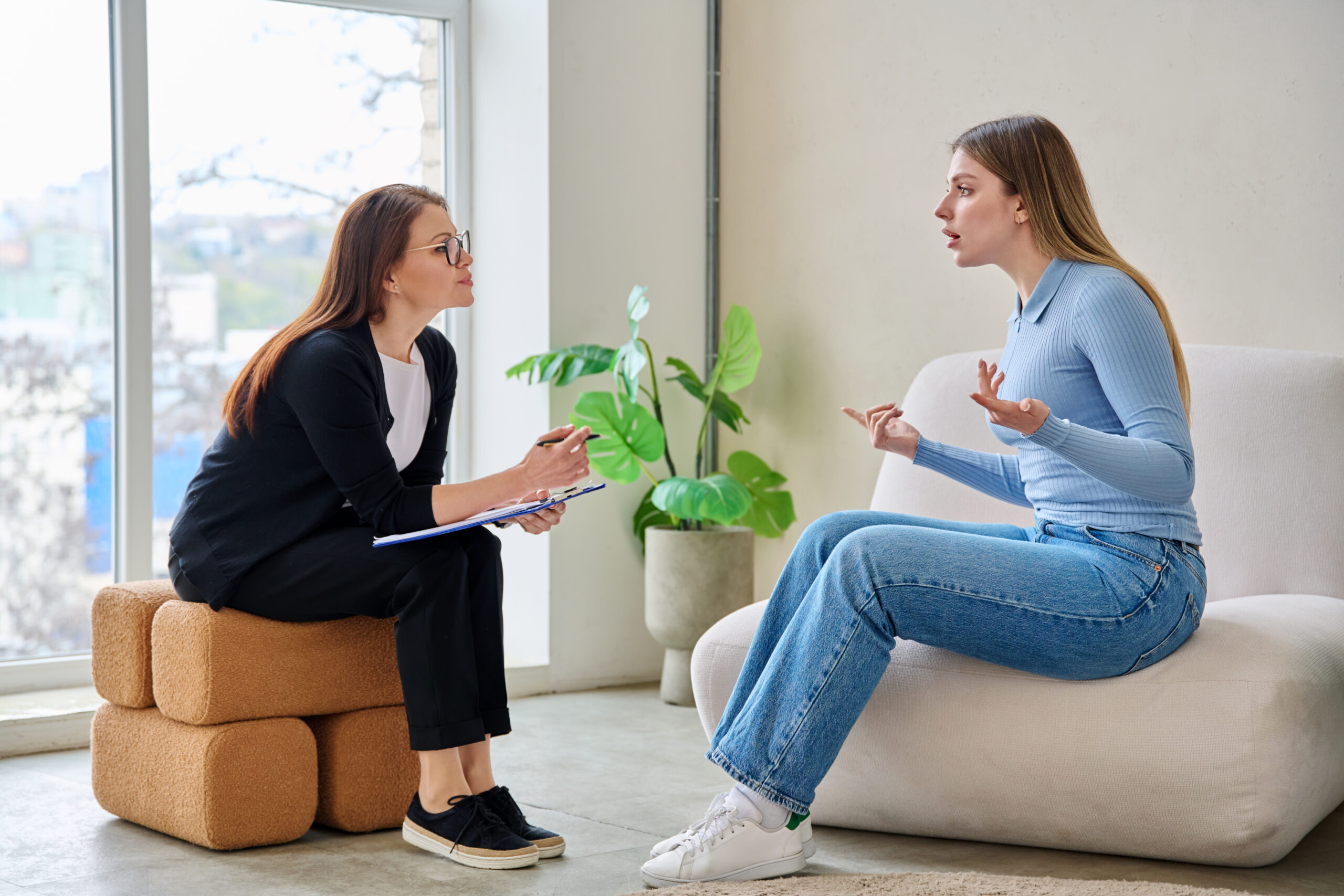 A woman talking to a therapist about signs a college student needs more than weekly therapy.