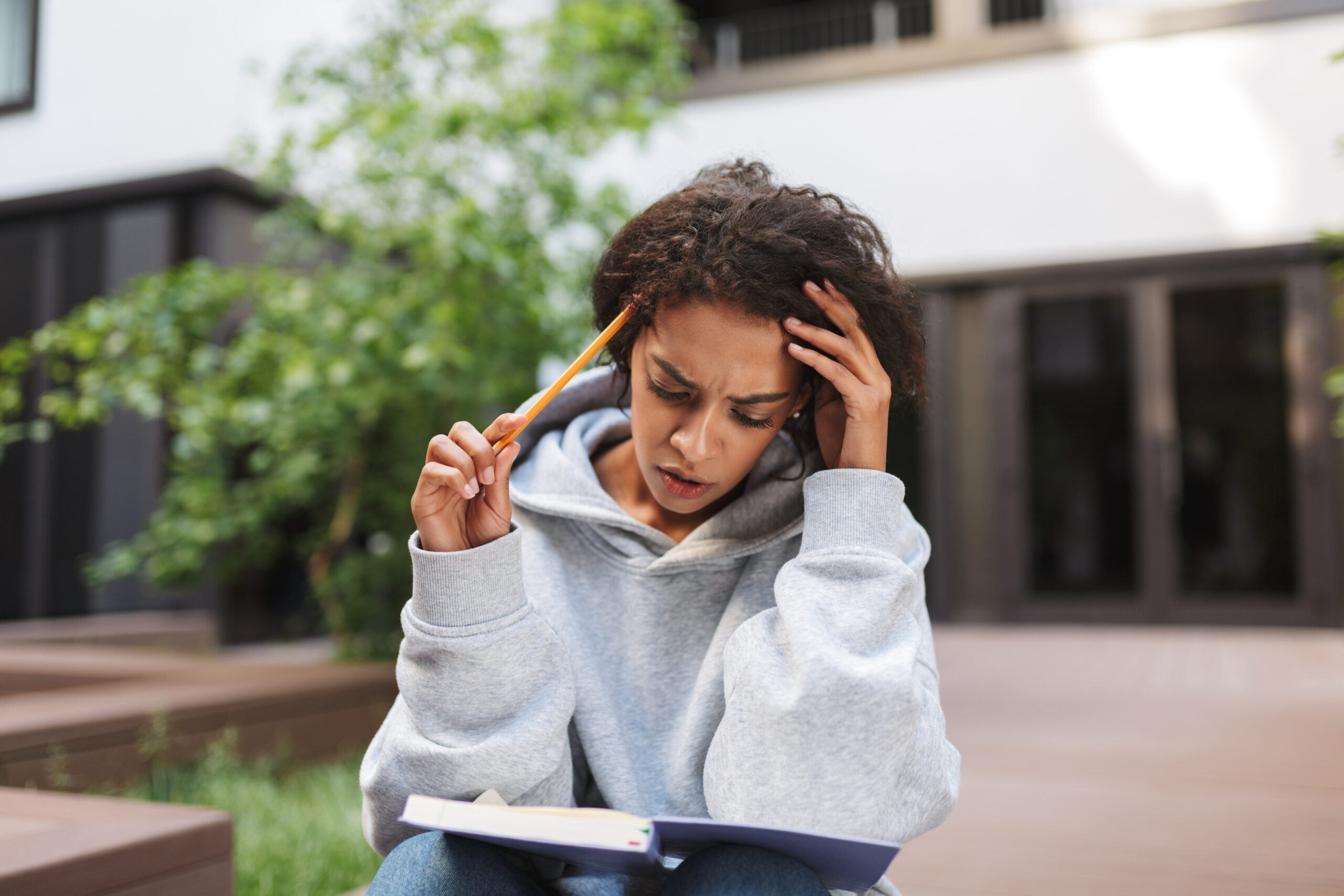 Woman studying outdoors with a book — calmer headspace, supported care