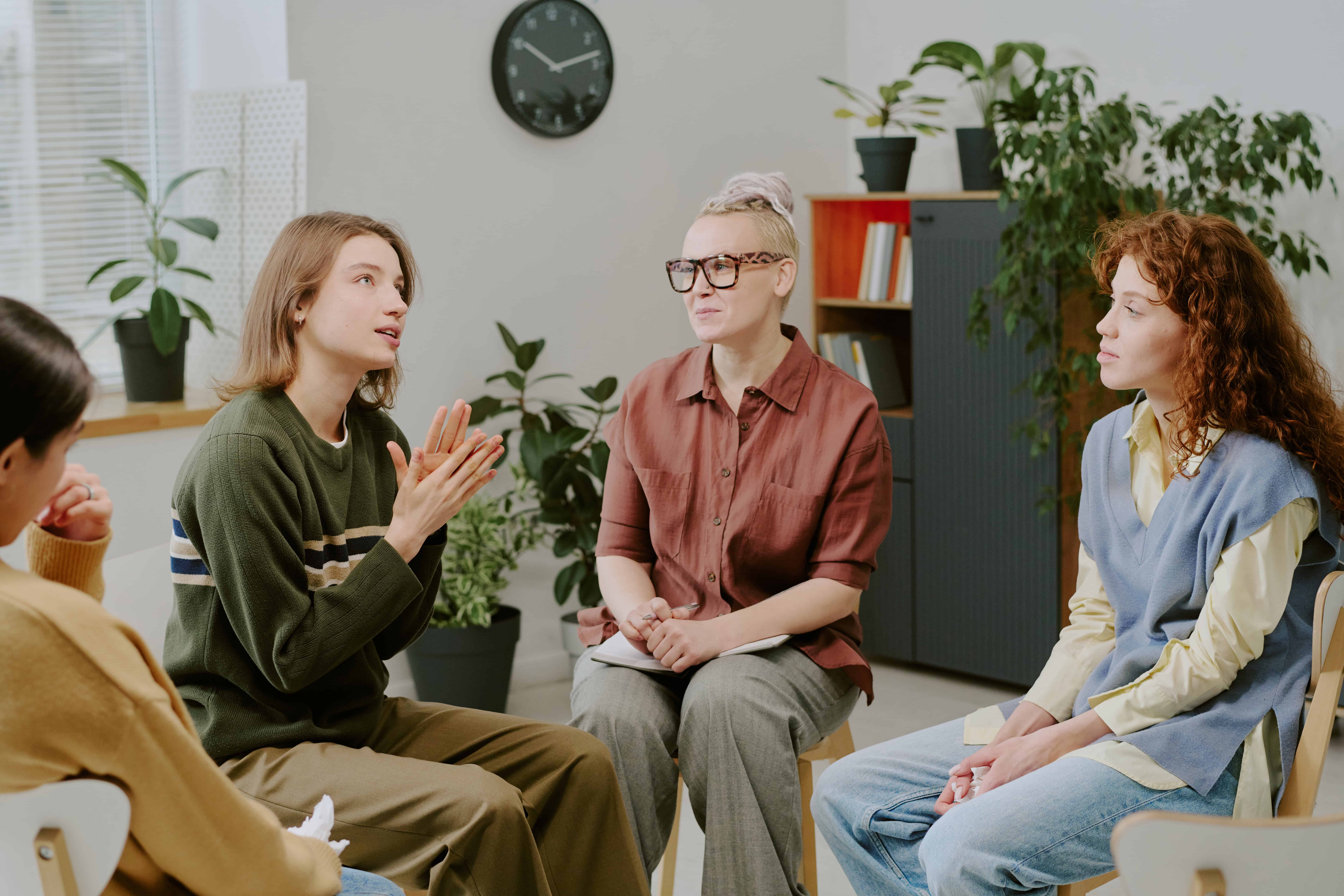 Women taking part in a supportive group therapy session in a bright, comfortable room