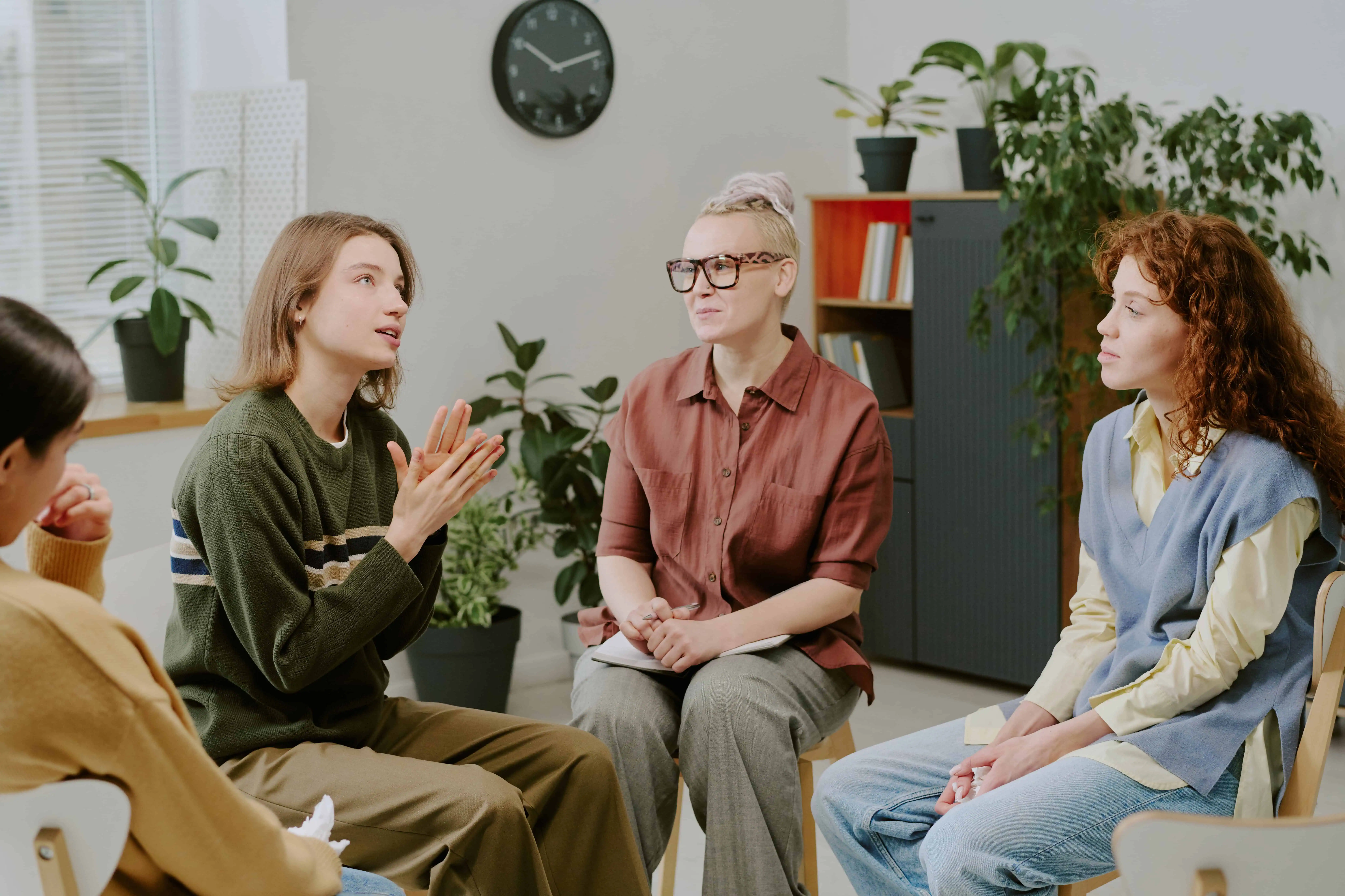 Women taking part in a supportive group therapy session in a bright, comfortable room