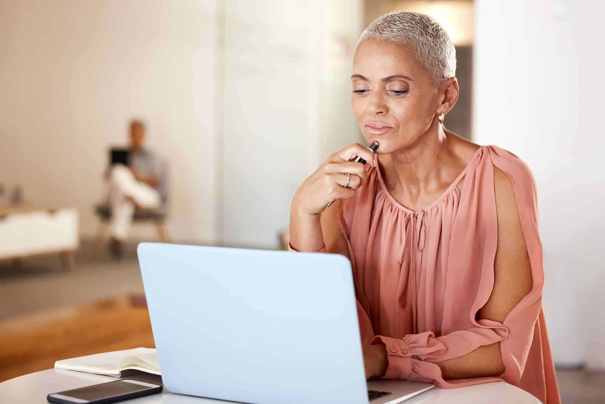 A woman sitting in front of a laptop reviewing insurance plans