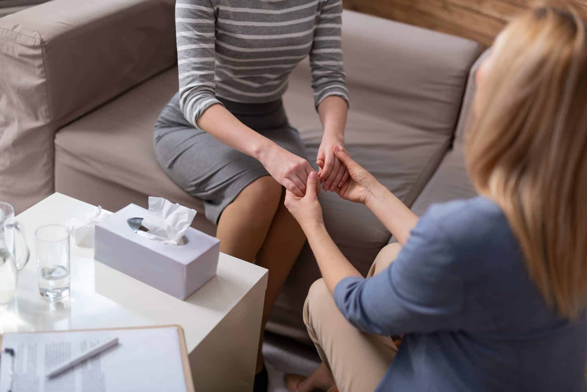 two women holding hands supporting each other during trauma recovery at Sol Women's Treatment in Riverside, California
