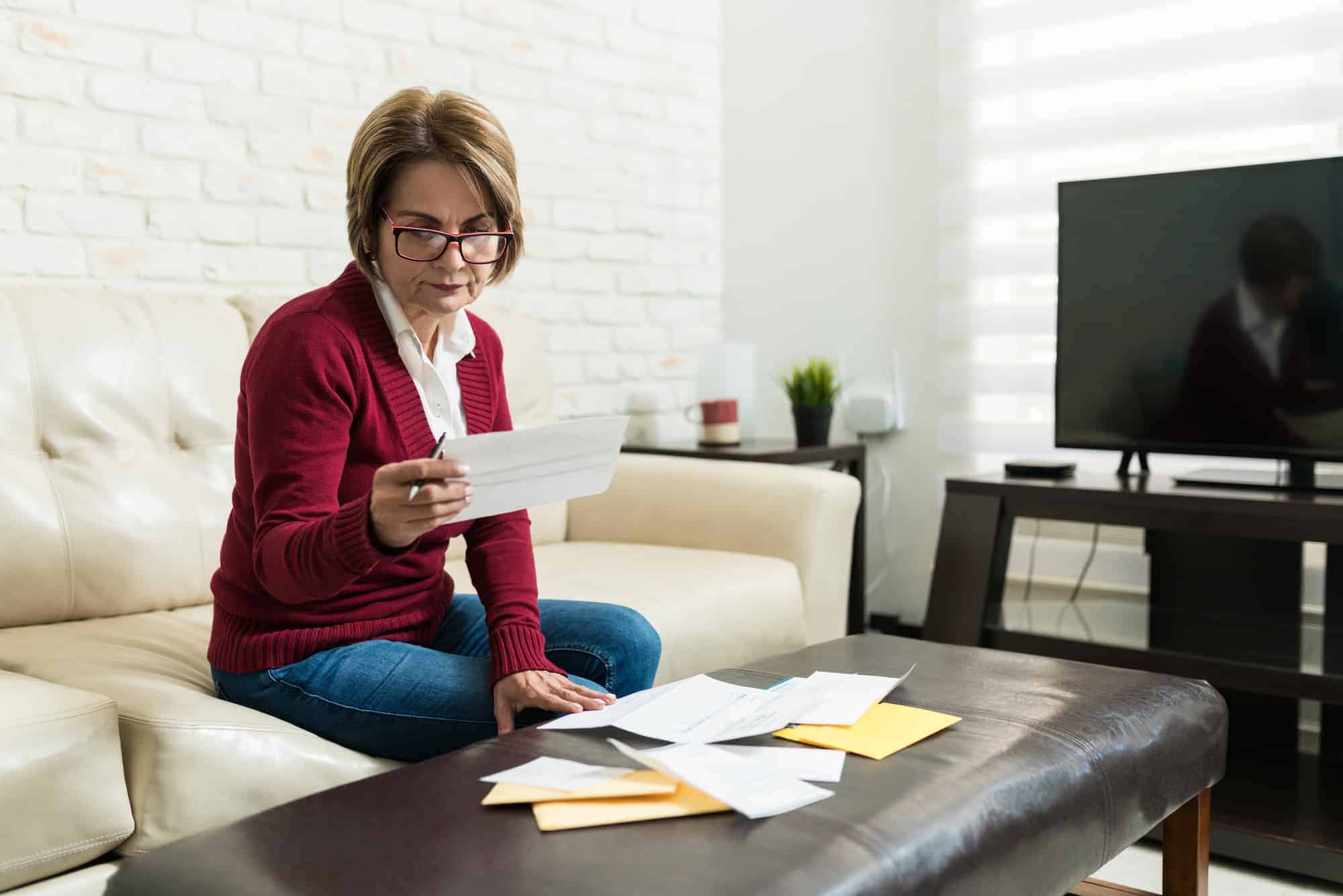 A woman reading her out-of-network insurance paperwork at home