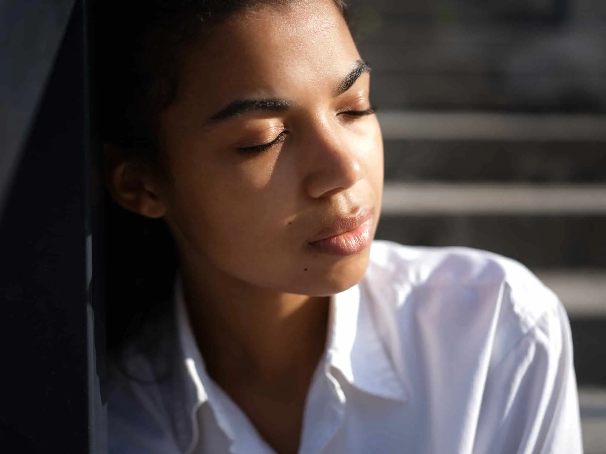 Woman with her eyes closed leaning against a wall