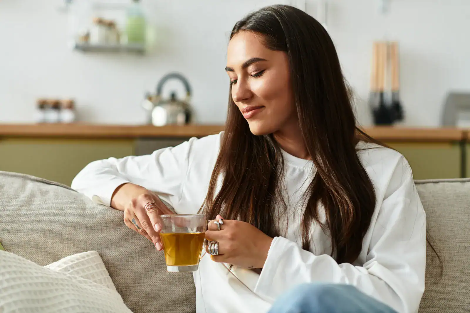 Woman relaxing on a couch with a cup of herbal tea in the evening