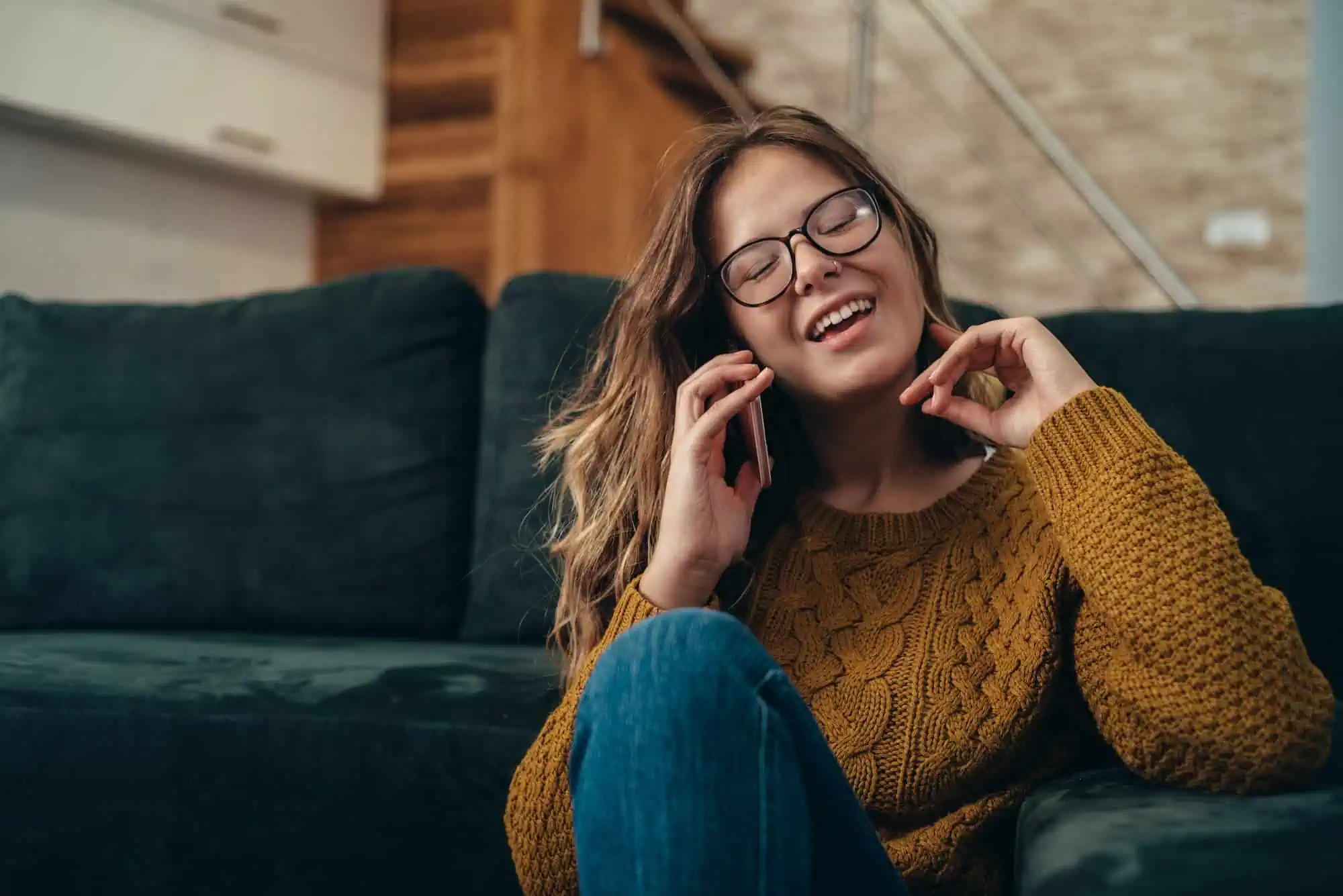 A woman smiles while talking on the phone at home, reaching out for support