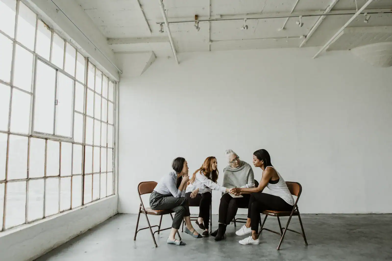 Small group of women talking and supporting each other in a bright room